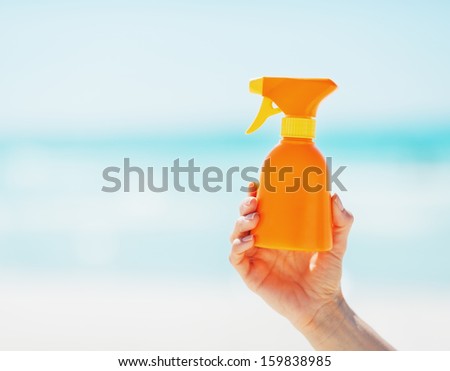 Closeup on bottle of sun screen creme in hand of woman
