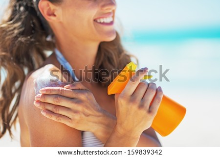 Closeup on smiling young woman applying sun block creme