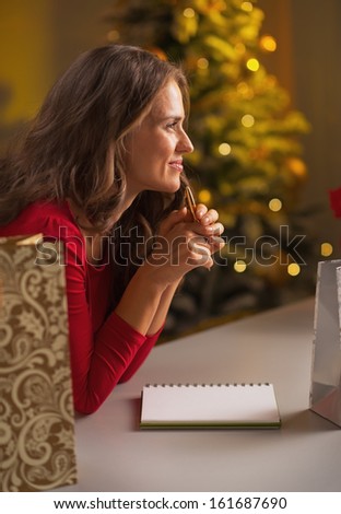 Thoughtful young woman making christmas list of presents