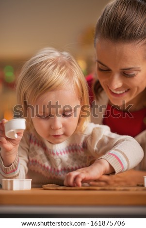 Baby helping other cutting christmas cookies from dough