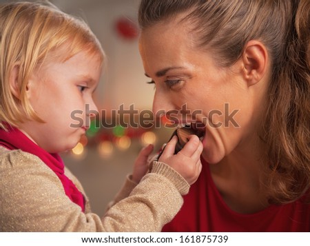 Baby giving mother bite of chocolate santa