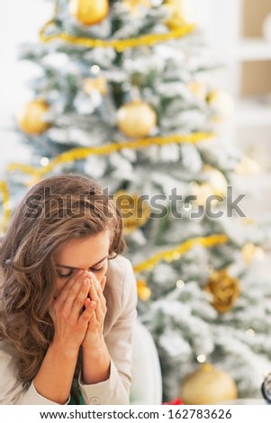 Stressed young woman sitting in front of christmas tree