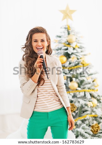 Happy young woman singing in front of christmas tree