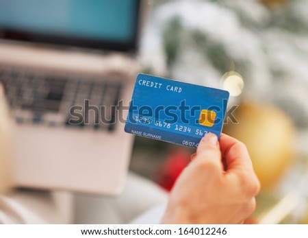 Closeup on credit card in hand of woman with laptop