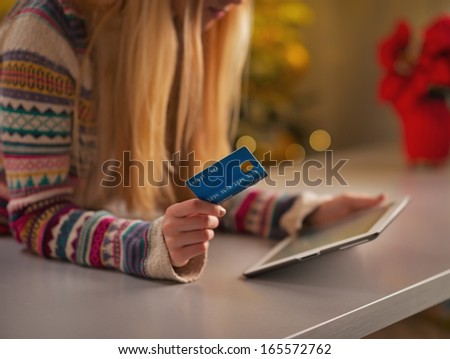 Closeup on teenage girl with credit card using tablet pc in christmas decorated kitchen