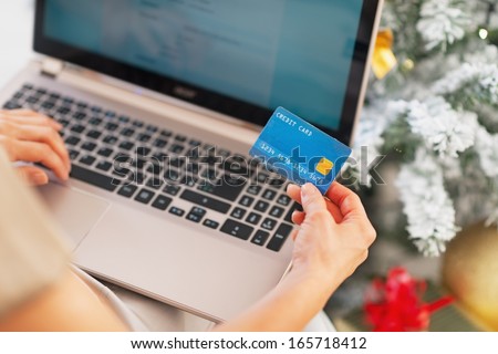 Closeup on young woman making online shopping near christmas tree