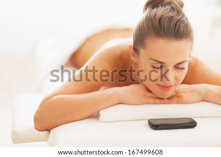 Relaxed young woman and cell phone laying on massage table