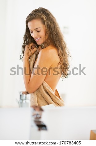 Portrait of happy young woman in towel in bathroom
