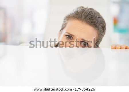 Frightened business woman looking out from desk
