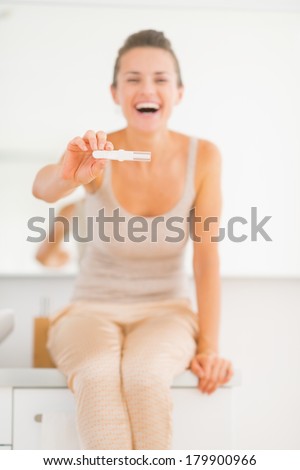 Happy young woman showing pregnancy test