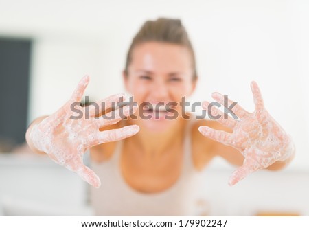 Closeup on smiling young woman showing hands with soap foam