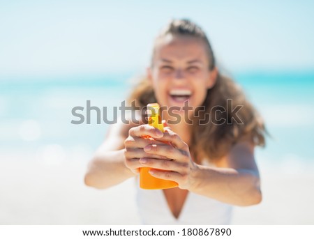 Closeup on young woman pointing bottle of sun block creme in camera