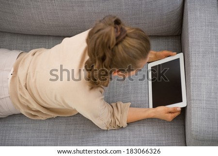 Young woman laying on sofa and using tablet pc