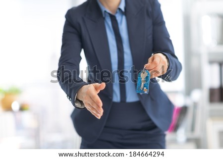 Closeup on happy business woman giving keys and stretching hand for handshake