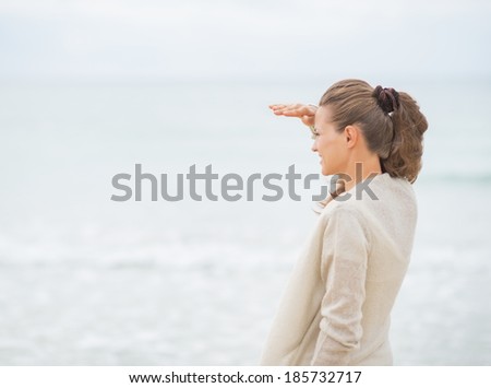 Young woman looking into distance while standing on cold beach standing