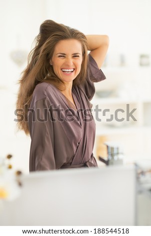 Portrait of happy young woman with long hair looking in mirror
