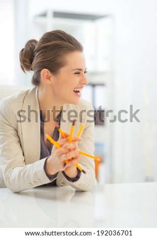 Laughing business woman holding pencils