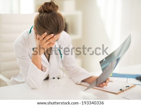 Stressed medical doctor woman with fluorography in office