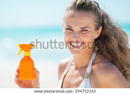 Happy young woman showing sun block creme