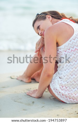 Relaxed young woman sitting on beach in the evening