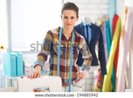 Portrait of happy seamstress in studio near sewing machine