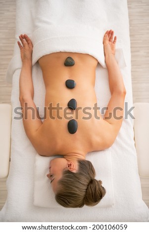 Relaxed young woman laying on massage table and receiving hot stone massage