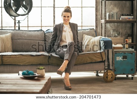 Happy business woman sitting in loft apartment on couch