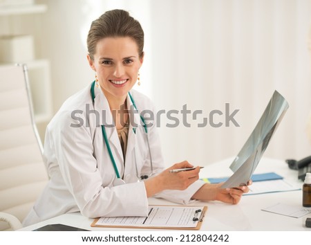 Portrait of happy doctor woman holding fluorography in office