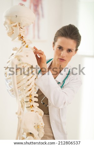 Doctor woman pointing on human skeleton anatomical model