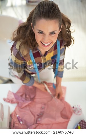Portrait of happy tailor woman working in studio