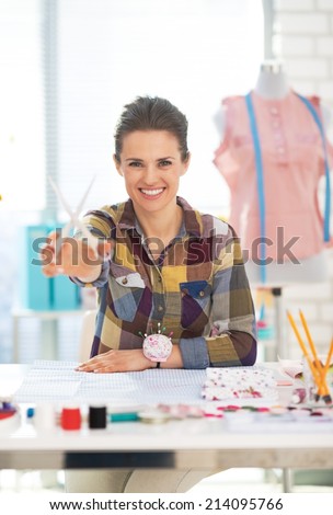 Happy tailor woman showing scissors