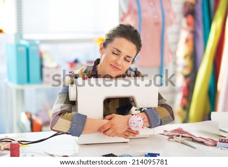 Happy tailor woman hugging sewing machine