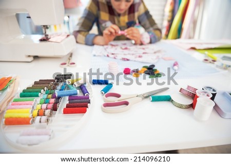 Closeup on working desk and tailor woman in background