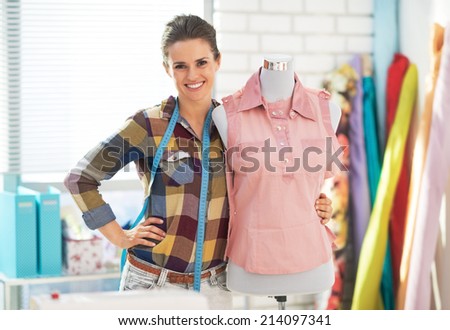 Portrait of happy tailor woman near mannequin
