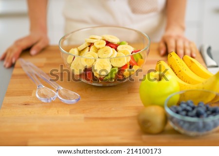 Closeup on young housewife making fresh fruit salad