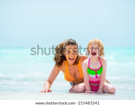 Portrait of cheerful mother and baby girl on sea shore