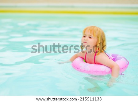 Baby girl with swim ring in swimming pool