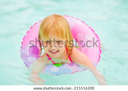Portrait of baby girl with swim ring swimming in pool