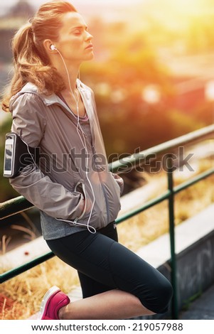 Portrait of relaxed fitness young woman in city in the evening