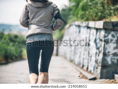 Closeup on fitness young woman jogging in the city park. rear view