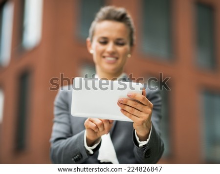 Closeup on business woman using tablet pc in front of office building