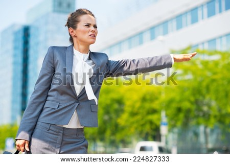 Portrait of concerned business woman in office district catching taxi