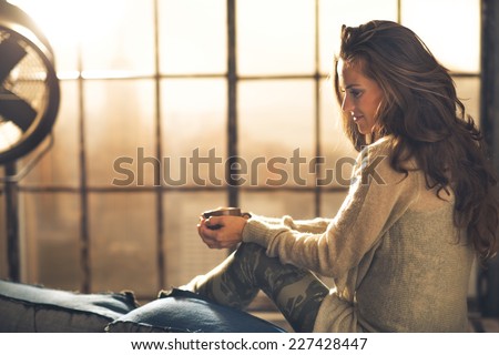 Young woman enjoying cup of coffee in loft apartment