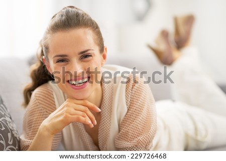 Portrait of happy young woman laying on sofa in living room