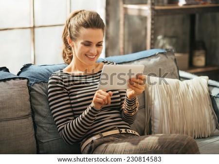 Happy young woman using tablet pc while sitting in loft apartment