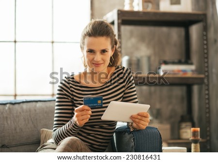 Portrait of happy young woman with credit card and tablet pc