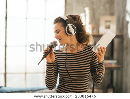 Happy young woman singing karaoke in loft apartment