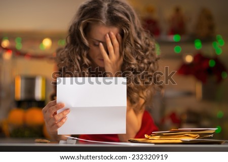 Closeup on frustrated young housewife with letter in christmas decorated kitchen