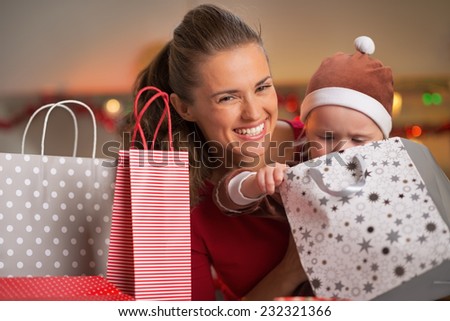 Smiling mother and baby looking in christmas shopping bag