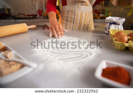 Closeup on young housewife drawing with flour on table